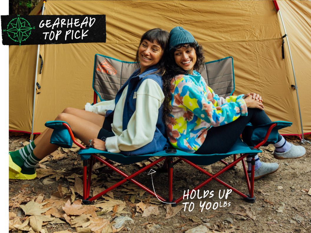 Two people sit back-to-back in a two-person camp chair. Text overlay reads: Gearhead Top Pick, holds up to 400lbs.